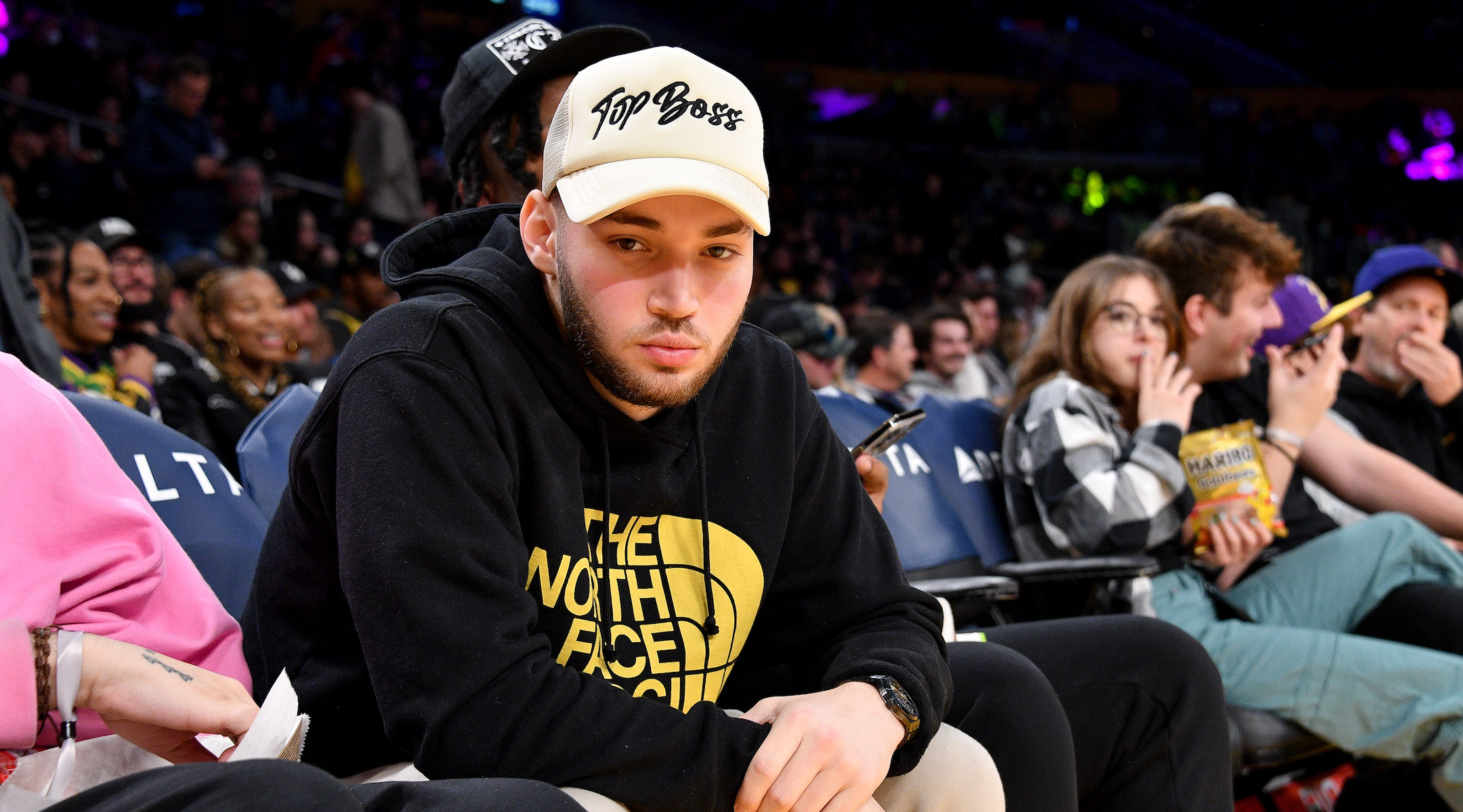 A young man watching a basketball game in a sweatshirt