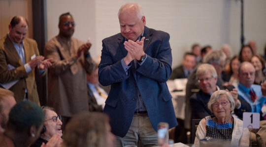 A politician stands and applauds an elderly woman at a gala dinner